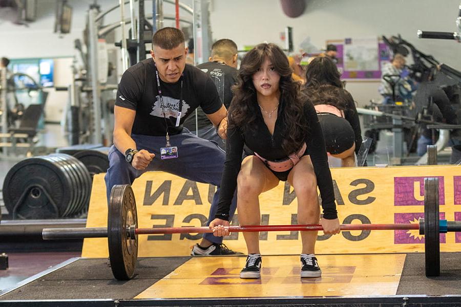 One student liftin a weight and another spotting